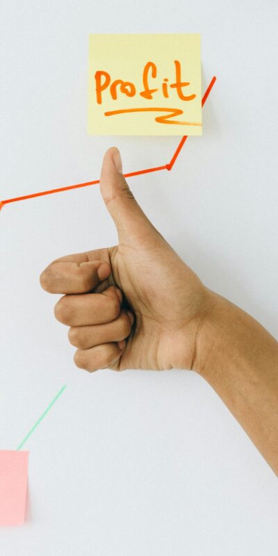 A hand giving a thumbs up in front of a profit growth chart, highlighting success.