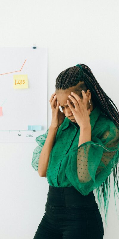Businesswoman in distress over financial graph showing loss indoors.