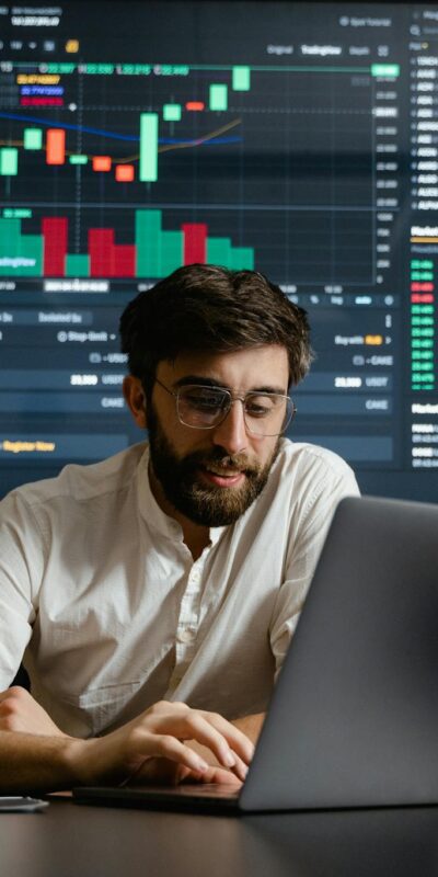 Male analyst studies cryptocurrency trends at a workstation with multiple displays showing market data.